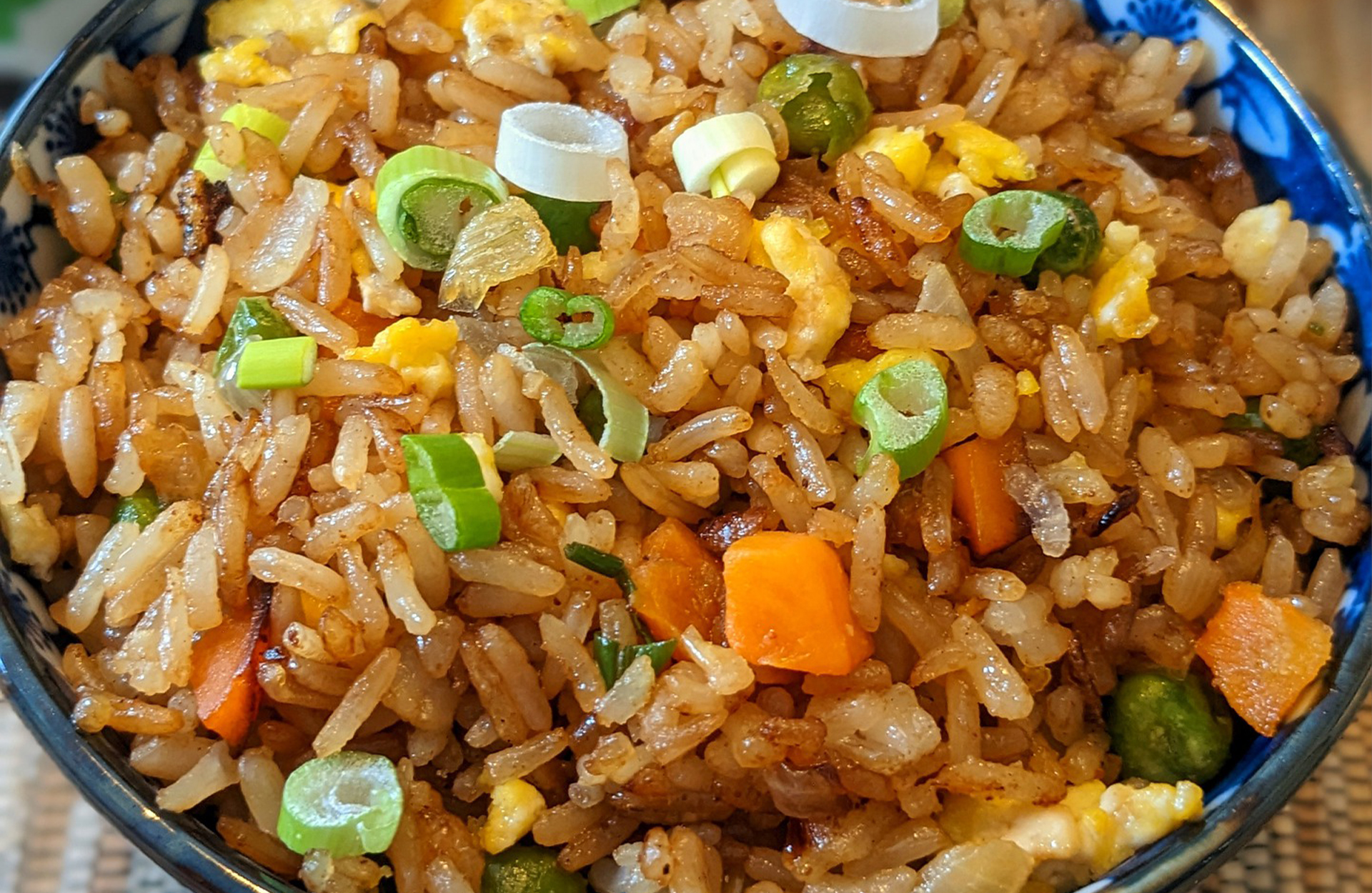 Fried rice with egg, scallions, and carrots in a blue bowl